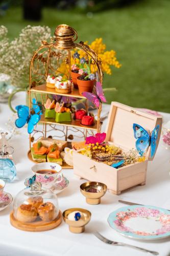 a table with a butterfly party with pastries and a basket of food at St. James' Court, A Taj Hotel, London in London