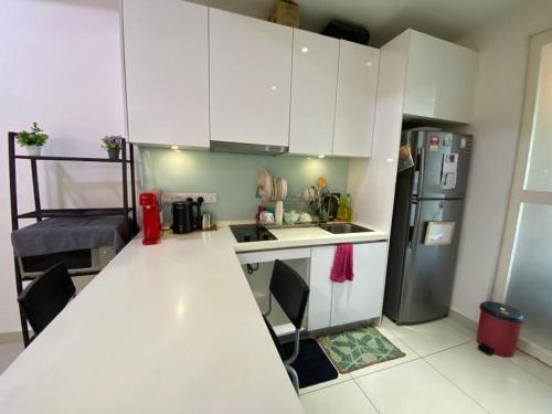 a small kitchen with white cabinets and a refrigerator at Islamic Santai Santai Homestay - Centrus Soho Cyberjaya in Cyberjaya