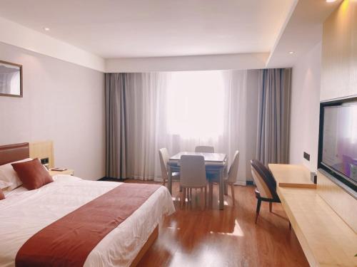 TaozhuangにあるGeli Hotel Zaozhuang High-Speed Railway Stationのベッド、テーブル、テレビが備わるホテルルームです。