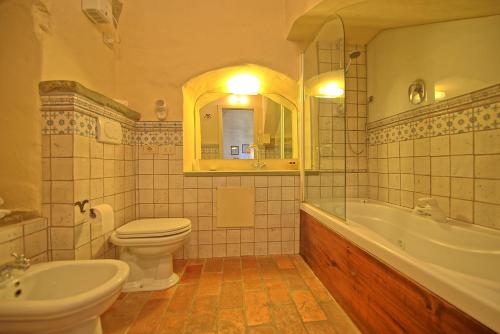 a bathroom with a toilet and a tub and a sink at Santa Flora by PosarelliVillas in Capolona