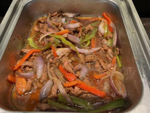 a metal pan filled with meat and vegetables at GreenTree Eastern Hotel Yiwu International Trade City in Yiwu