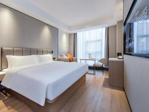 a bedroom with a large white bed and a flat screen tv at GreenTree Eastern Hotel Chongqing Jiefangbei International Airport Lushan Subway Station in Chongqing