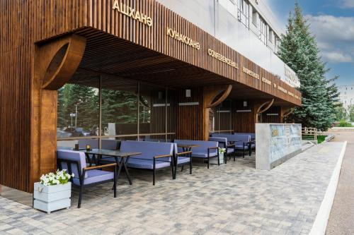 a restaurant with tables and chairs in front of a building at Kamarooms Business Hotel & Spa in Naberezhnyye Chelny