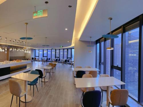 a cafeteria with tables and chairs and windows at GreenTree Eastern Hotel Yiwu International Trade City in Yiwu