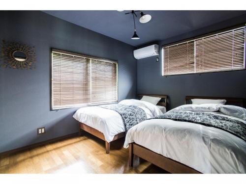 館山市にあるLittle Hermit - Vacation STAY 39645vの青い壁と窓が特徴の客室で、ベッド2台が備わります。
