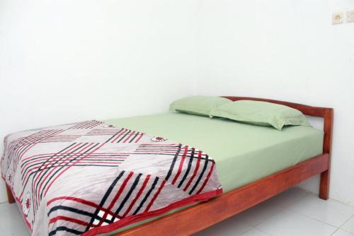 a bed in a room with a white wall at Liahz Lodge in Kelimutu