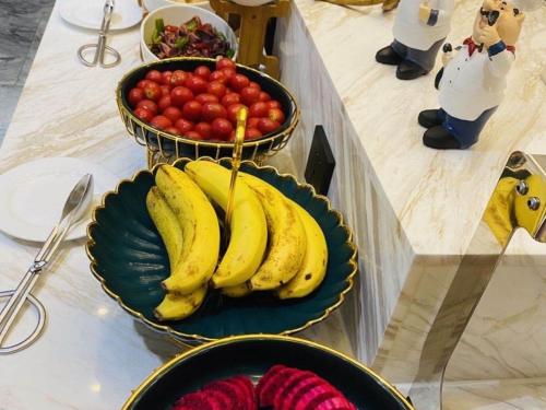 a plate of bananas and a bowl of tomatoes on a table at GreenTree Eastern Hotel Huai'an Suning Plaza West Huaihai Road in Huai'an