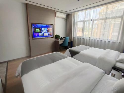 a hotel room with two beds and a flat screen tv at GreenTree Eastern Hotel Huai'an University in Huai'an