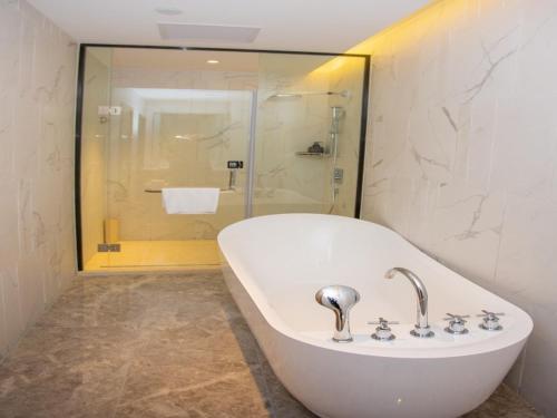 een badkamer met een wit bad en een douche bij GreenTree Eastern Hotel Binzhou Zhonghai International Convention and Exhibition Center in Binzhou