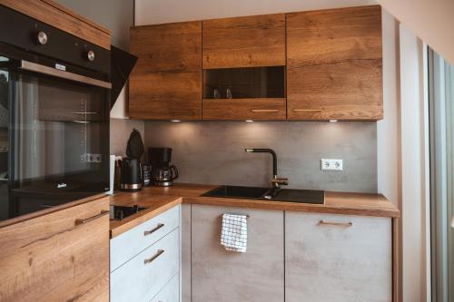 a kitchen with wooden cabinets and a sink at Ferienweingut SerwaziWein in Mesenich