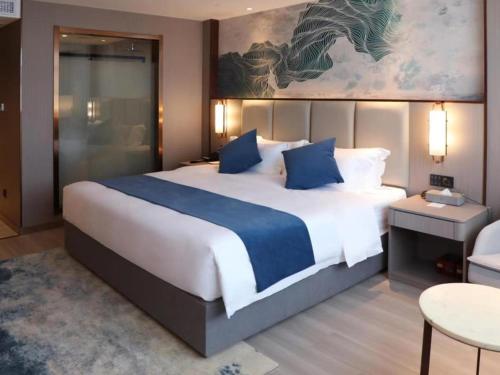 a bedroom with a large bed with blue pillows at GreenTree Eastern Taizhou Gaogang North Yangzijiang Road Mingfa Plaza in Taizhou