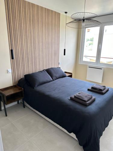 - une chambre avec un lit bleu et 2 serviettes dans l'établissement Appartement neuf contemporain, à Lourdes