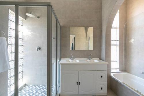 ヨハネスブルグにあるTranquil & Secure 3bed home 2km 2 Emmarentia Damのバスルーム(シンク2台、シャワー、バスタブ付)