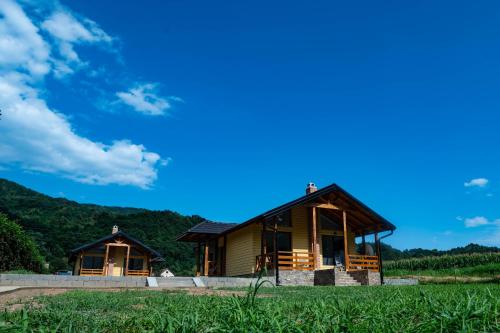 a house in a field with a blue sky at Apartmani Zavičaj Gornja Trešnjica in Ljubovija