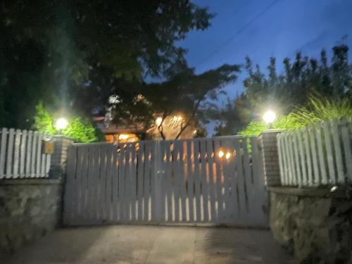 a white fence in front of a house at night at Nas San lower apartment in Vrdnik