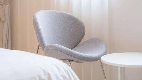a gray chair sitting next to a white table at Geoje Mongdol Beach H Avenue Hotel in Geoje 