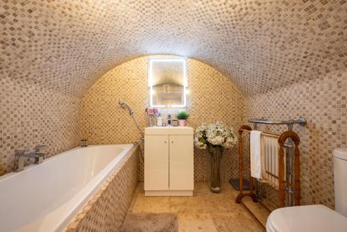 a bathroom with a bath tub and a toilet at Niru Experience Hidden Gem in Chelsea in London