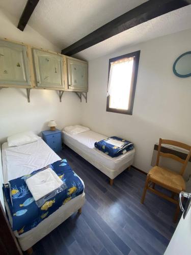 - 2 lits dans une chambre avec une chaise et une fenêtre dans l'établissement Appt T3 magnifique vue mer, à Saint Pierre La Mer