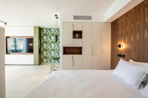 a bedroom with a white bed with a wooden headboard at Beach Side- Ceasar Luxury Amazing Pool Eilat in Eilat