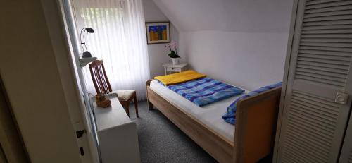 a small bedroom with a bed and a chair at Fewo Hackländer in Hemmoor