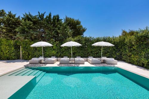 a swimming pool with lounge chairs and umbrellas at B&B Villa EraGea in Matino