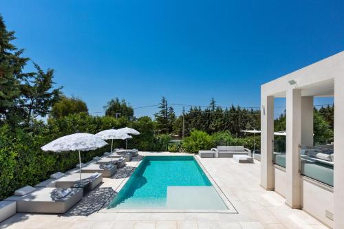 a swimming pool with lounge chairs and umbrellas at B&B Villa EraGea in Matino