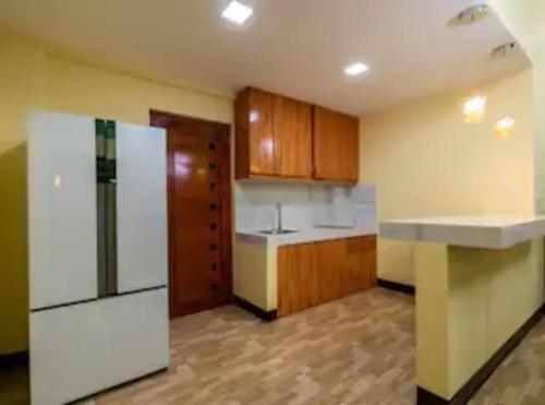 a kitchen with a white refrigerator and wooden cabinets at CIDNYLAND FARM AND RESORT TANAY in Tanay