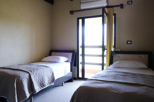 two beds in a room with a window at Hotel Vila Bruci in Burrel