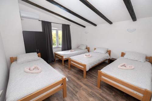 a room with three beds with pink slippers on them at Greenoasis Bihac in Bihać