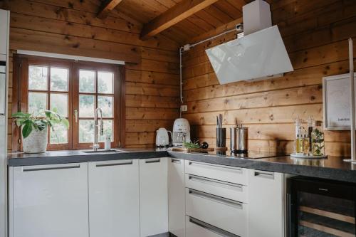 a kitchen with white cabinets and wooden walls at Life & Cooking Holiday Home in Ermelo