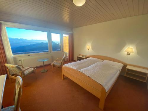a bedroom with a bed and a large window at Bärnsicht Panorama Hotel in Wasen