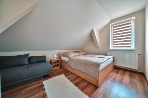a bedroom with a bed and a couch and a window at Kriszta Deluxe Vendégház in Újfehértó