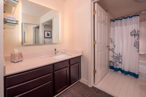 a bathroom with a sink and a mirror and a shower at Residence Inn Fairfax Merrifield in Merrifield