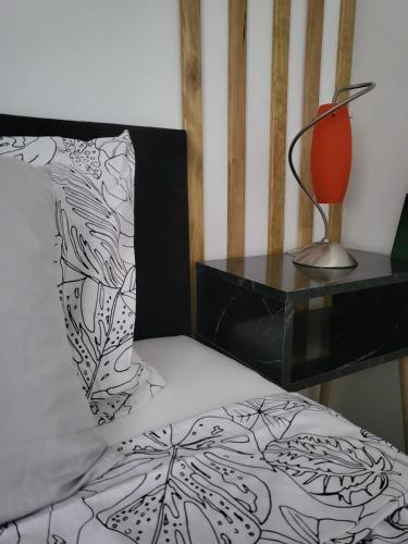 a bed with a black and white pillow and a lamp at Industrial Home Vršac in Vršac
