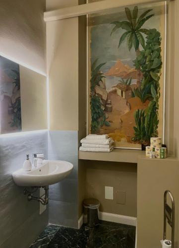 un baño con lavabo y una pintura en la pared en B&B Piazza Duomo al 55, en Voghera