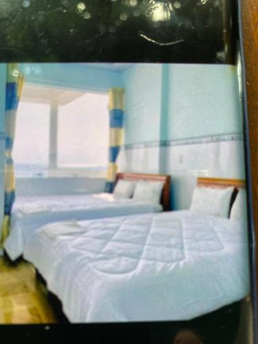 two twin beds in a room with a window at Vân tiến in Rach Gia