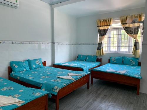 a room with three beds and a window at Vân tiến in Rạch Giá
