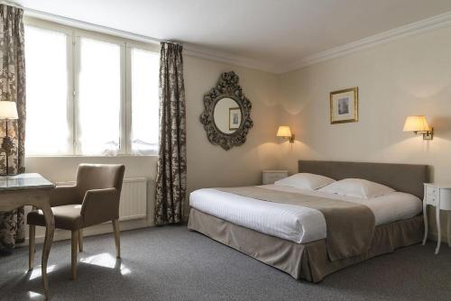 a bedroom with a bed and a desk and a mirror at Hôtel de L'univers in Arras