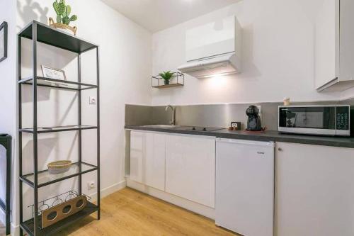 une cuisine avec des armoires blanches et un micro-ondes dans l'établissement Le Little Blue : au coeur du centre historique, à Dijon