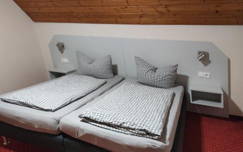 two beds sitting in a room with wooden ceilings at Pension Schneider, Ferienwohnung in Bad Gögging