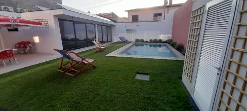 a woman sitting in a lawn chair next to a swimming pool at Sargaço Suíte Pool and Beach in Póvoa de Varzim