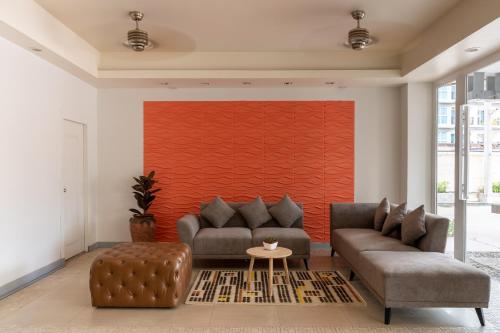 una sala de estar con 2 sofás y una pared roja. en Heeton Concept Hotel Pattaya by Compass Hospitality en Pattaya centro
