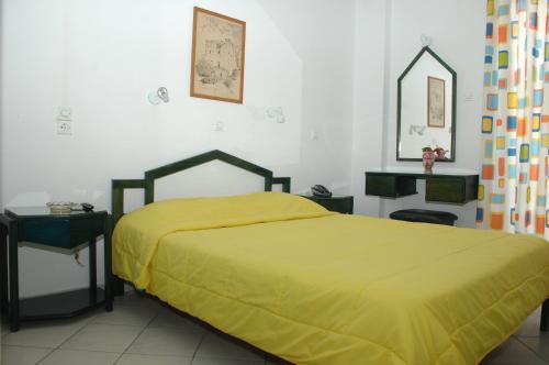 a bedroom with a bed with a yellow bedspread at Koronis Hotel in Tolo