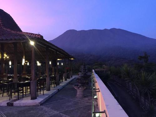 a restaurant with a view of the mountains at night at De Summit Villa & View in Puncak