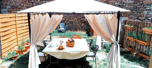 a table under a white umbrella in a garden at Los Arroyos in San Martín de la Vega del Alberche