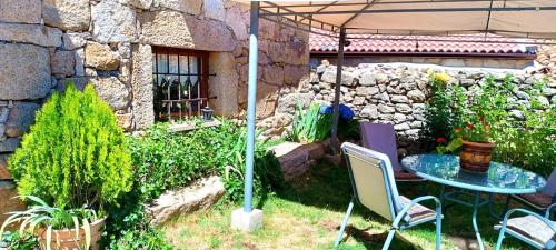 a garden with a table and chairs under an umbrella at Los Arroyos in San Martín de la Vega del Alberche