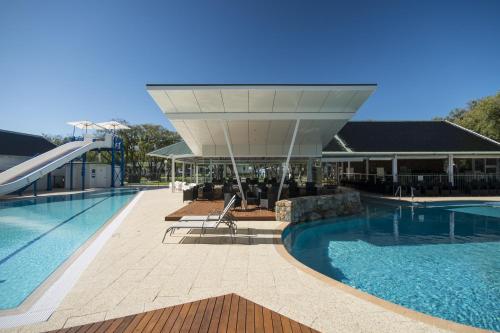 a large swimming pool with a slide and a building at Mandalay Holiday Resort and Tourist Park in Busselton