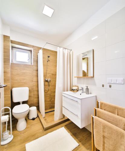 a white bathroom with a toilet and a shower at Kriszta Deluxe Vendégház in Újfehértó
