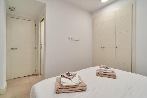 een witte slaapkamer met handdoeken op een bed bij Luxurious Two Bed in Torrox