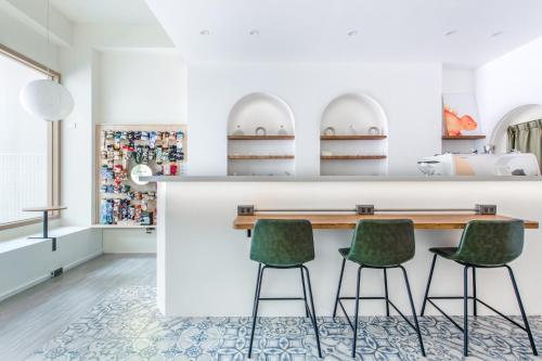 a kitchen with a counter and two green chairs at Long Stay Here in Tainan